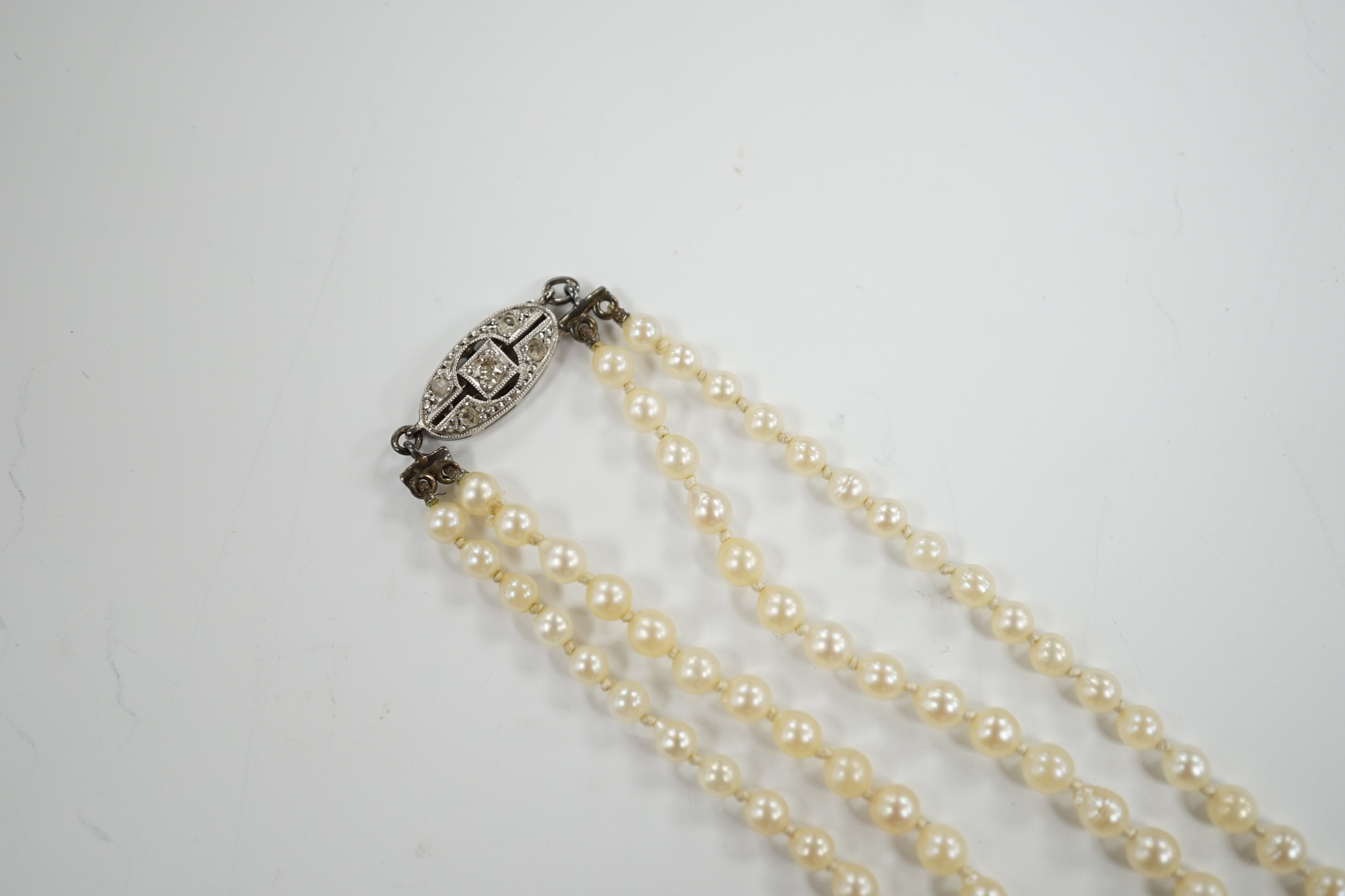 A 1930's twin strand graduated cultured pearl necklace, with 14ct, plat and diamond chip set clasp, 50cm.